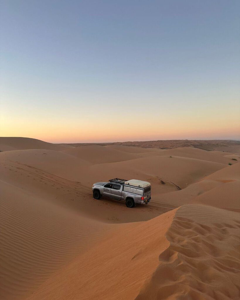 A group of travelers enjoying the golden dunes of Wahiba Sands, a must-see desert in Oman