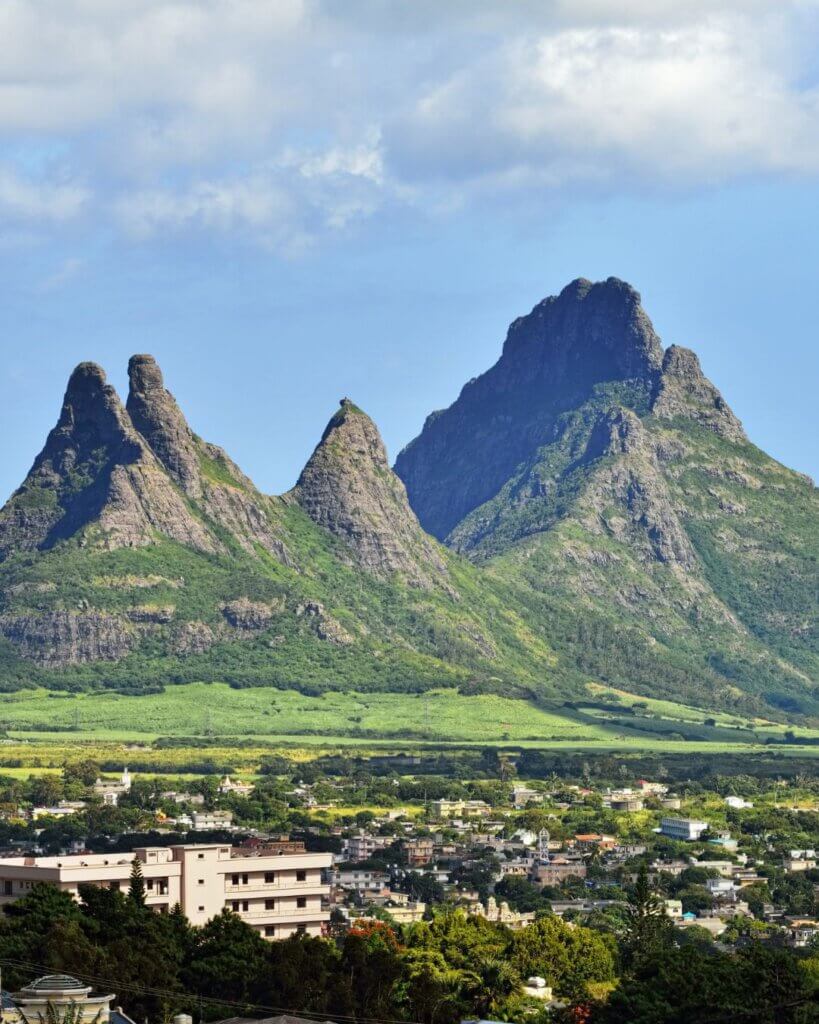 Immerse yourself in the vibrant colors of Mauritius, where azure skies meet emerald mountains in a picturesque setting.