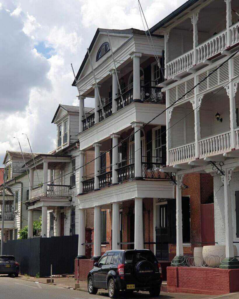 Colonial houses along Waterkant street in Paramaribo, Suriname, with lush greenery and riverside views