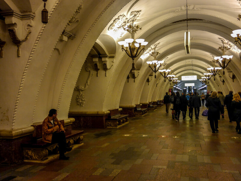 Spacious waiting area at Arbatskaya metro station in Moscow, featuring arched ceilings and marble pillars.