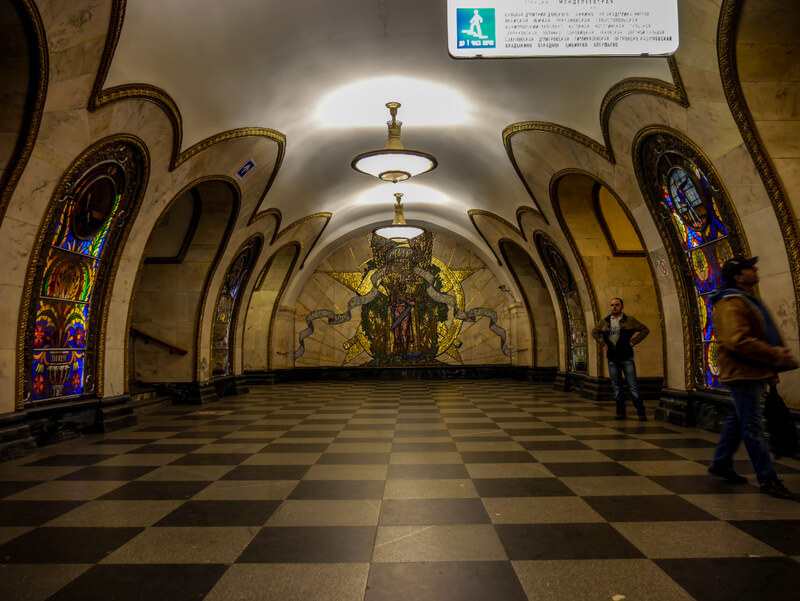 Novoslobodskaya metro station in Moscow, showcasing its famous stained-glass windows and golden lighting.